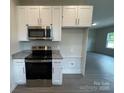 Modern kitchen boasts stainless steel appliances, granite countertops, and sleek white cabinetry at 1312 7Th St, Statesville, NC 28677