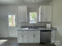 Bright kitchenette with white cabinets, granite countertops, stainless dishwasher and door to exterior at 1312 7Th St, Statesville, NC 28677