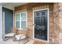 Welcoming front door with brick surround and rocking chairs on the covered porch at 348 Zocalo Dr, Gastonia, NC 28056