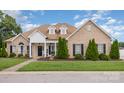 Well-maintained brick home features manicured lawn, mature trees, and inviting front porch for curb appeal at 4406 Atkinson Way, Monroe, NC 28110