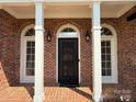 Close-up of the front door with arched windows, decorative black metal door, and brick facade with stately white columns at 456 Brook Valley Ne Ct, Concord, NC 28025