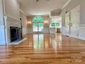 Bright, open-concept living room featuring gleaming hardwood floors, fireplace, large window, and view into the updated kitchen at 456 Brook Valley Ne Ct, Concord, NC 28025