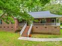 Charming brick home featuring a large front porch with white railings, surrounded by mature trees and landscaping at 4620 Binwhe Ln, Gastonia, NC 28052