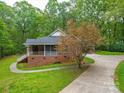Charming brick home with a screened-in porch, complemented by lush greenery and a well-maintained driveway at 4620 Binwhe Ln, Gastonia, NC 28052