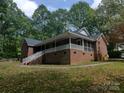 Side view of a well-maintained brick home with a cozy screened-in porch and surrounding mature trees at 4620 Binwhe Ln, Gastonia, NC 28052