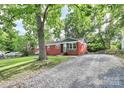 Charming brick home with a gravel driveway framed by lush greenery, blending classic architecture with a serene, natural setting at 4913 Winchester St, Charlotte, NC 28208