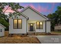 Charming home features white siding, black framed windows, and a covered front porch at 705 Sunderland Sw Rd, Concord, NC 28027