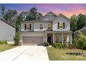 Inviting two-story home with a two-car garage, well-maintained lawn, and covered front porch during dusk at 941 Rachel Anne Dr, Belmont, NC 28012