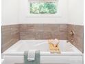 Relaxing soaking tub with a tiled surround and a window view in a serene bathroom at 10743 Ola Dr, Fort Mill, SC 29707