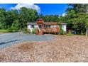 Inviting exterior with a pergola-covered porch surrounded by lush greenery and a gravel driveway at 10743 Ola Dr, Indian Land, SC 29707