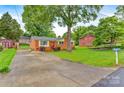 Charming brick home with a red door, landscaped yard, long concrete driveway, and mature trees at 1405 8Th Nw Ave, Conover, NC 28613