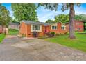 Charming brick home with a red door, landscaped yard, and long concrete driveway at 1405 8Th Nw Ave, Conover, NC 28613