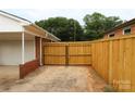 View of backyard with wooden fence and gate leading to the garage of this charming home at 1421 Thompson Ave, Charlotte, NC 28216