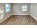 A bedroom featuring wood-look flooring, two windows providing natural light, and fresh, neutral paint throughout at 2214 Grimes St, Charlotte, NC 28206