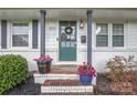 Close-up of front door with wreath, potted flowers, and brick steps at 3809 Topsfield Rd, Charlotte, NC 28211