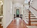 Entryway featuring hardwood floors, staircase with white railing, and black trimmed entry door at 6128 Fletcher Cir, Charlotte, NC 28226