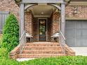 Inviting front porch with brick steps, seating and a dark front door with glass panes at 6128 Fletcher Cir, Charlotte, NC 28226