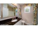 Well-lit bathroom featuring a granite countertop, ample mirror space, and modern decor at 107 Asmodean Ln, Troutman, NC 28166