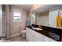 Well-lit bathroom with a black granite countertop, white cabinets, a window, and neutral tiling at 127 Asmodean Ln, Troutman, NC 28166