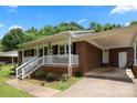 Brick home with a covered porch and attached carport, offering convenient parking and outdoor space at 128 Wandering Ln, Bessemer City, NC 28016