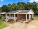 Brick home with a covered porch and attached carport, offering convenient parking and outdoor space at 128 Wandering Ln, Bessemer City, NC 28016