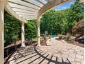 Relaxing outdoor patio area with pergola, landscaping, and view of the pool at 13837 Grand Palisades Pkwy, Charlotte, NC 28278