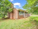 Side view of a brick home with green shutters and large trees at 202 College Ave, Shelby, NC 28152