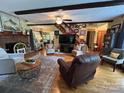 Spacious living room with hardwood floors, a brick fireplace, beamed ceilings, and staircase access at 2815 Penny Park Dr, Gastonia, NC 28052