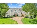 Beautiful white brick home featuring a lush green lawn, stately trees, and a welcoming driveway at 469 Valley Run Dr, Waxhaw, NC 28173