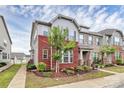 Charming townhome showcasing brick accents, complemented by a well-manicured lawn and lush landscaping at 5391 Orchid Bloom Dr, Fort Mill, SC 29707