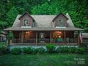 Charming log home with a covered front porch, lush landscaping, and American flag at 95 Odell Ct, Taylorsville, NC 28681