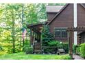 Side view of a log cabin featuring lush landscaping, a small dog house and an American flag at 95 Odell Ct, Taylorsville, NC 28681