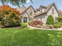 Charming stone-accented home with lush landscaping including mature trees and green lawn at 1404 Lookout Cir, Waxhaw, NC 28173