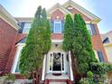 Close-up of the brick home's front door, framed by lush greenery and mature landscaping at 16012 Caranna Ct, Charlotte, NC 28277