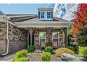Inviting front porch with stone pillars and seating surrounded by colorful landscaping at 1905 Tranquility Blvd, Lancaster, SC 29720