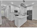 Modern white kitchen featuring an island, stainless steel appliances, and a sleek, minimalist lighting fixture at 1933 St Mark St, Charlotte, NC 28216