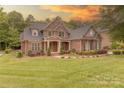 Beautiful brick home with a well-manicured lawn and tasteful landscaping against the sunset at 4113 Hoffmeister Dr, Waxhaw, NC 28173