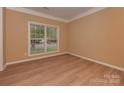 A sunlit bedroom with a large window, neutral walls, and modern light-colored wood flooring at 5607 Fulton Ridge Dr, Indian Trail, NC 28079