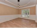 Formal dining room features wainscoting, wood floors, a modern chandelier, and large window at 5607 Fulton Ridge Dr, Indian Trail, NC 28079
