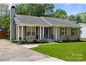 Charming one-story home with a beautifully landscaped front yard and gray brick exterior at 6406 Old Meadow Rd, Charlotte, NC 28227