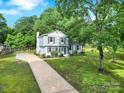 Charming two-story home with light blue siding, dark shutters, green lawn, and mature trees at 8514 Timber Crest Cir, Charlotte, NC 28226