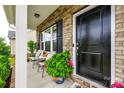 Close-up of a charming front porch with seating, plants, and a black front door at 922 Bunker Trce, Rock Hill, SC 29730