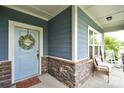 Inviting front porch with stylish stone accents, seating, and a welcoming wreath on the front door at 104 Rockridge Point Dr, Mooresville, NC 28117