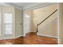 Bright foyer showcasing hardwood floors, a staircase with white railing, and natural light from the window at 12824 Harvest Time Ct, Charlotte, NC 28278