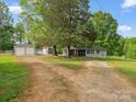 Charming single-story home with large trees, gravel driveway, detached garage, and outbuildings at 195 Bluebird Ln, Salisbury, NC 28146