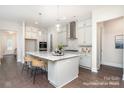 Bright kitchen features a spacious island with seating, stainless steel appliances and gray cabinets and hardwood flooring at 20396 Queens St, Cornelius, NC 28031
