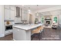 Open-concept kitchen featuring a large island with seating, pendant lights, gray cabinetry, and stainless steel appliances at 20396 Queens St, Cornelius, NC 28031