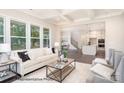 Cozy living room showcases large windows, coffered ceilings, and is open to the kitchen and dining area at 20396 Queens St, Cornelius, NC 28031