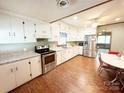 Well-lit kitchen featuring stainless steel appliances, granite countertops, white cabinets, and eat-in dining area at 211 Spruce St, Badin, NC 28009
