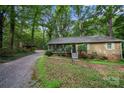 Charming single-story home featuring a screened front porch, long driveway, and set amidst a lush, wooded landscape at 3000 Low Gap Rd, Waxhaw, NC 28173